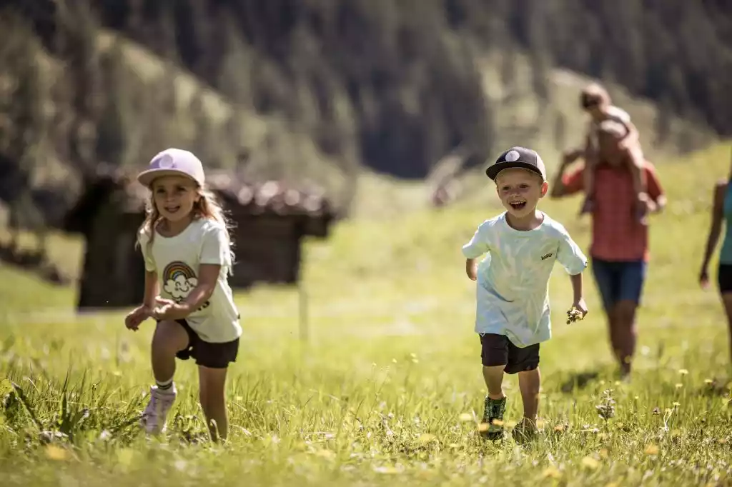 Auf dem Bild ist eine Familie beim Wandern zu sehen, die Kinder laufen fröhlich voraus fort.